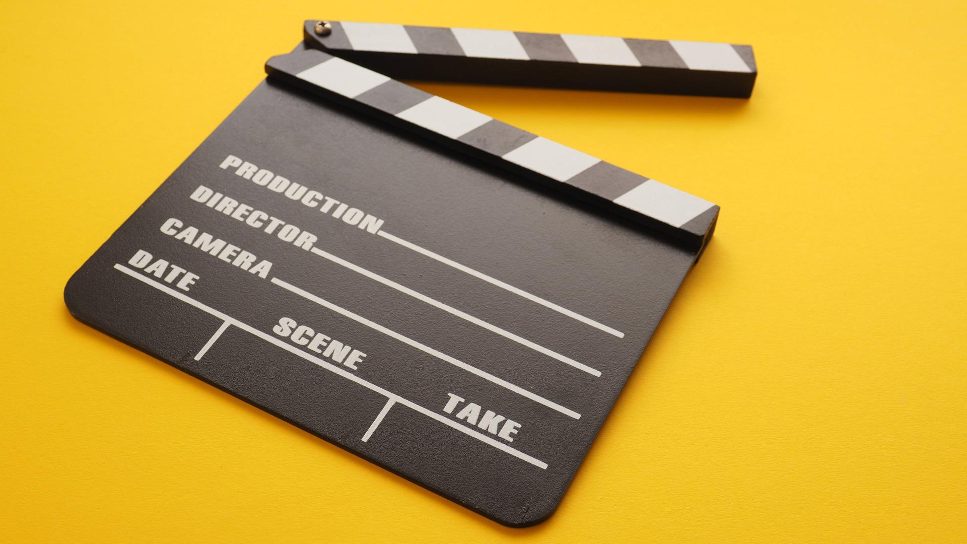 Eine Filmklappe liegt auf einem gelben Hintergrund. Eine Filmklappe liegt auf einem gelben Hintergrund.