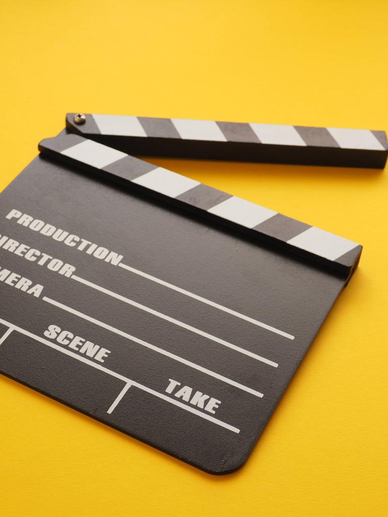 Eine Filmklappe liegt auf einem gelben Hintergrund.