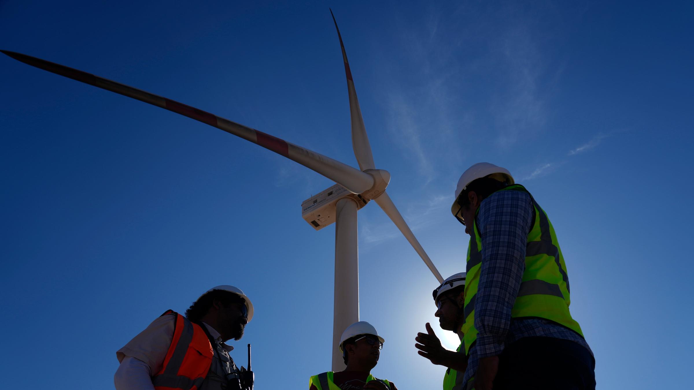 Ingenieure im Gespräch neben einer Windturbine in der Lekela Windenergie Station, in der Nähe von Ras Ghareb, etwa 300 Kilometer von Kairo entfernt