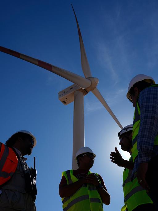 Ingenieure im Gespräch neben einer Windturbine in der Lekela Windenergie Station, in der Nähe von Ras Ghareb, etwa 300 Kilometer von Kairo entfernt