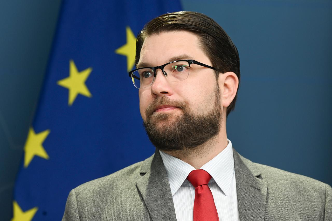 Ein Mann mit Anzug und Krawatte, Brille und Vollbart, vor der Europafahne.