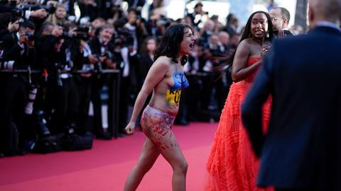 Eine Frau mit bemaltem Oberkörper stürmt den roten Teppich beim Filmfestival in Cannes.