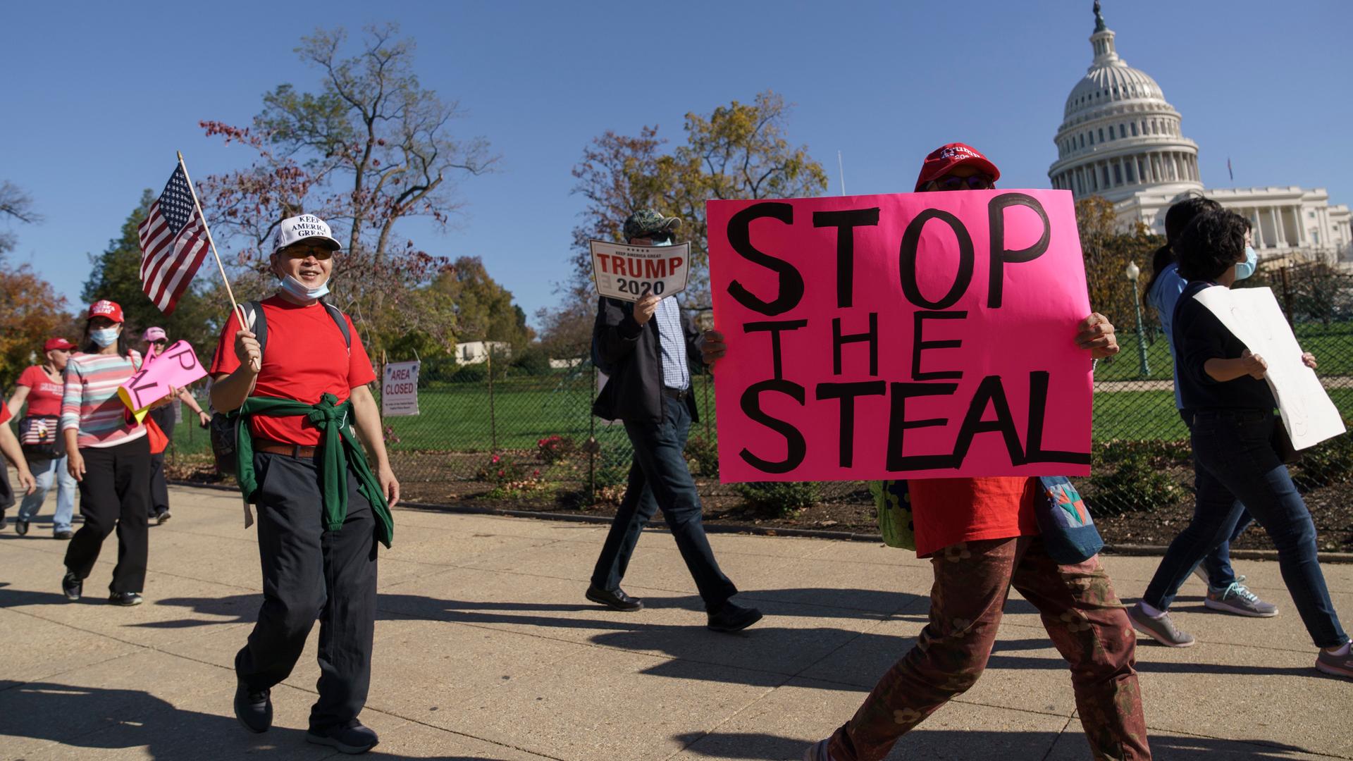 Unterstützer von Donald Trump laufen nach der Präsidentschaftswahl 2020 vor dem Kapitol entlang. Eine Person trägt ein Schild mit der Aufschrift "stop the steal". Unterstützer von Donald Trump laufen nach der Präsidentschaftswahl 2020 vor dem Kapitol entlang. Eine Person trägt ein Schild mit der Aufschrift "stop the steal".