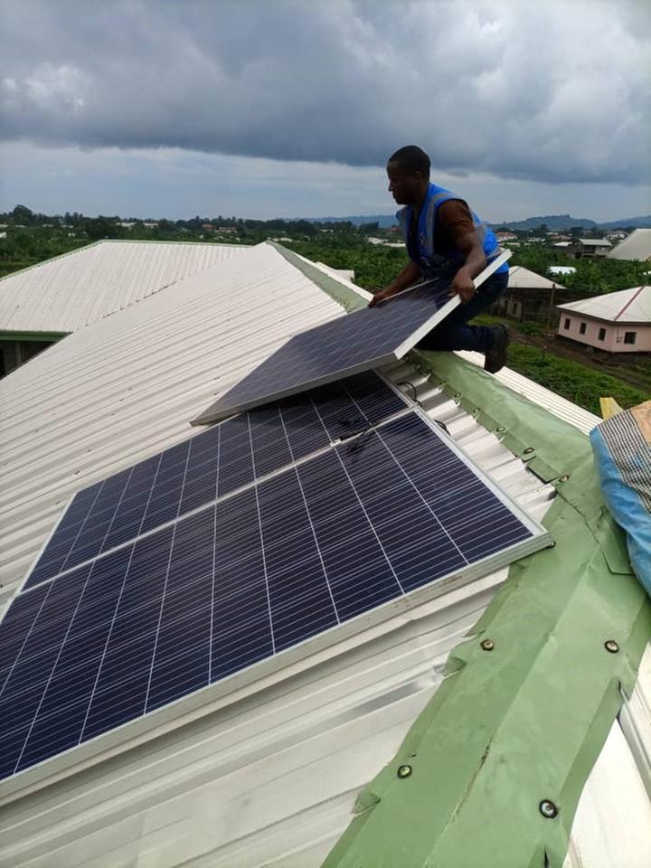 Ein Mann installiert Solarpanele auf einem Dach.