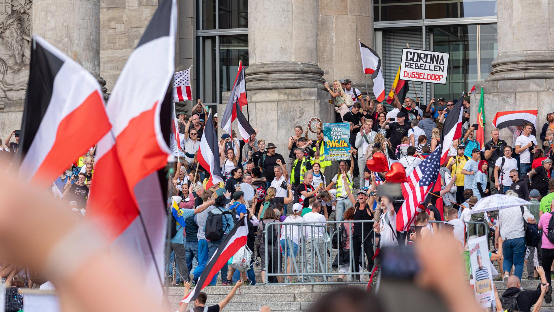 Mehrere hundert Menschen stehen mit Plakaten gegen die Corona-Maßnahmen sowie mit Reichsflaggen vor dem Berliner Reichstag. Das Foto ist im August 2020 entstanden. Mehrere hundert Menschen stehen mit Plakaten gegen die Corona-Maßnahmen sowie mit Reichsflaggen vor dem Berliner Reichstag. Das Foto ist im August 2020 entstanden.
