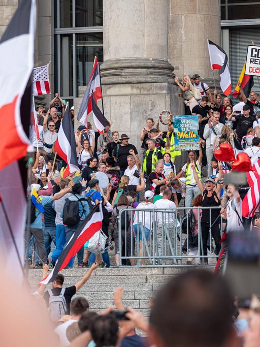 Mehrere hundert Menschen stehen mit Plakaten gegen die Corona-Maßnahmen sowie mit Reichsflaggen vor dem Berliner Reichstag. Das Foto ist im August 2020 entstanden.