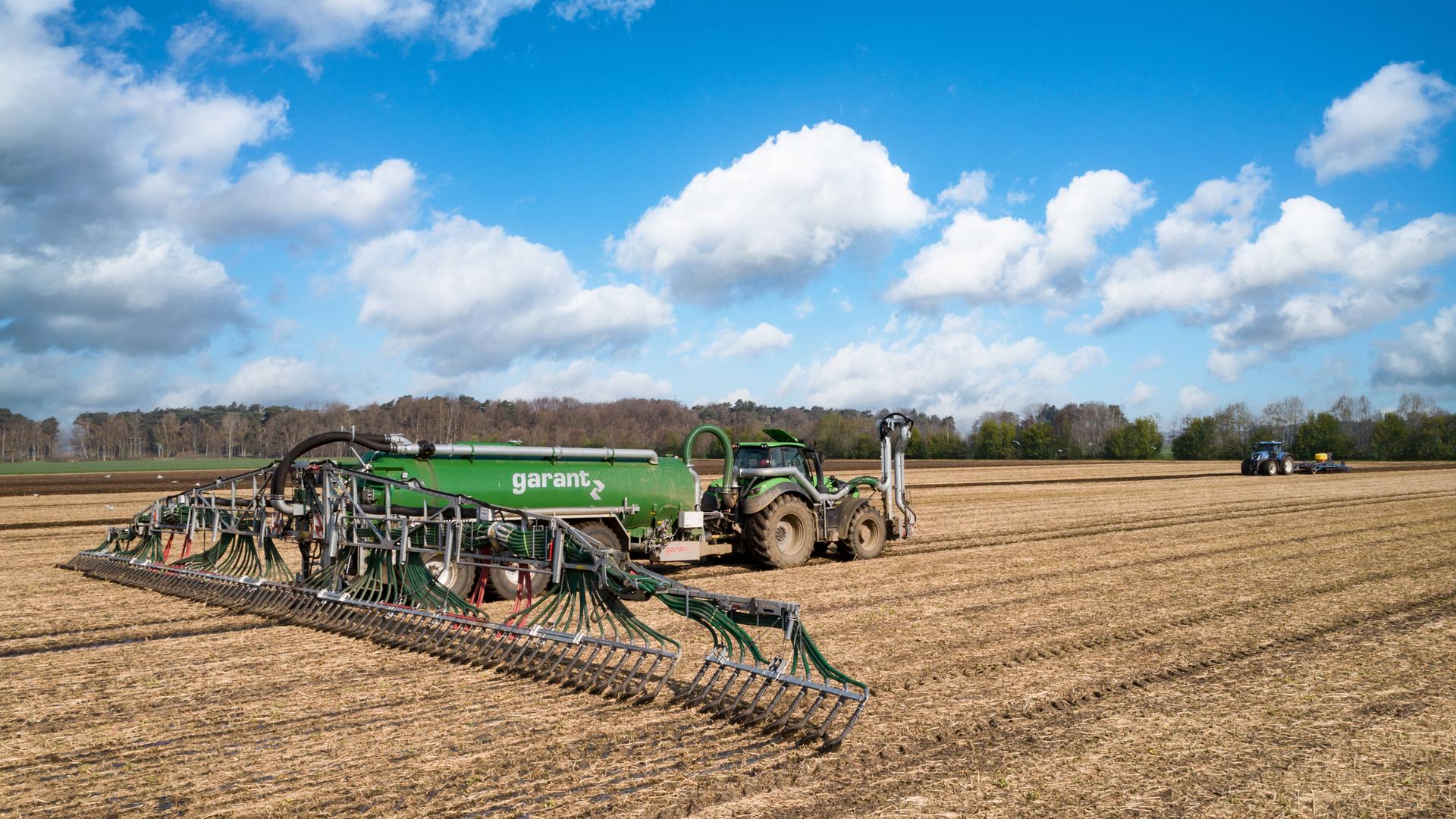 Traktor zieht einen Anhänger, der Gülle versprüht Traktor zieht einen Anhänger, der Gülle versprüht