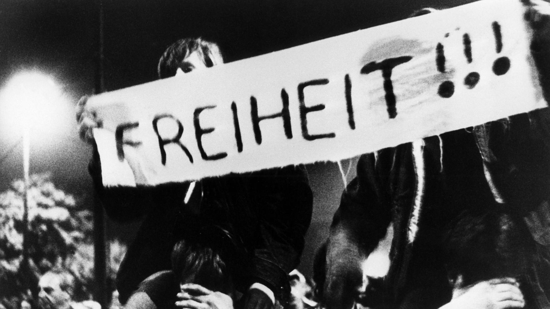 Zwei Männer, Teilnehmer des friedlichen Demonstrationszuges am 09.10.1989 durch die Leipziger Innenstadt, halten ein Banner mit der Aufschrift "Freiheit!" Zwei Männer, Teilnehmer des friedlichen Demonstrationszuges am 09.10.1989 durch die Leipziger Innenstadt, halten ein Banner mit der Aufschrift "Freiheit!"