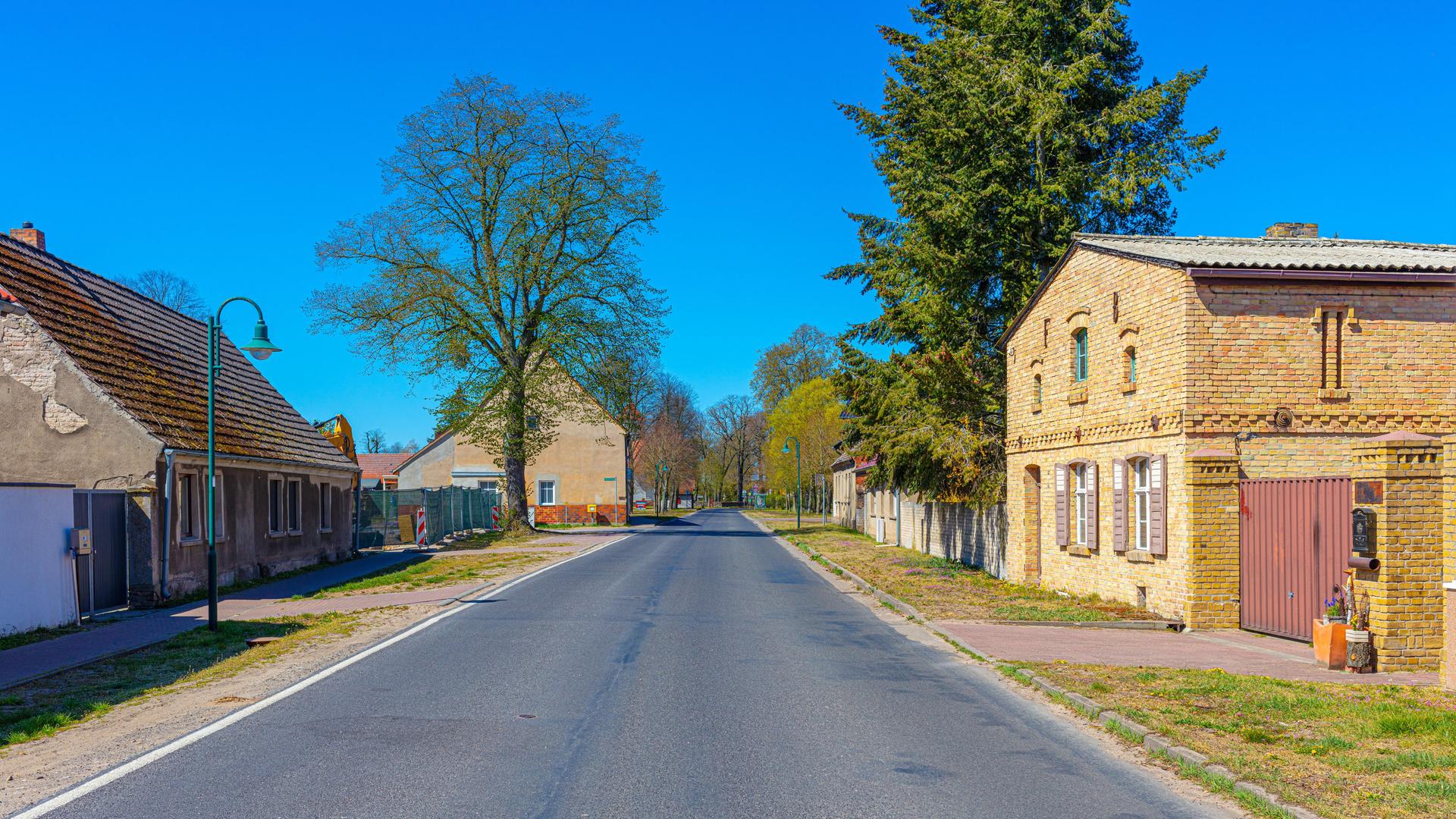 Eine Landstraße, die durch ein Dorf führt. Rechts und links sind alte Häuser zu sehen - Beispiele für historische Dorfarchitektur mit denkmalgeschützte Fassaden.
