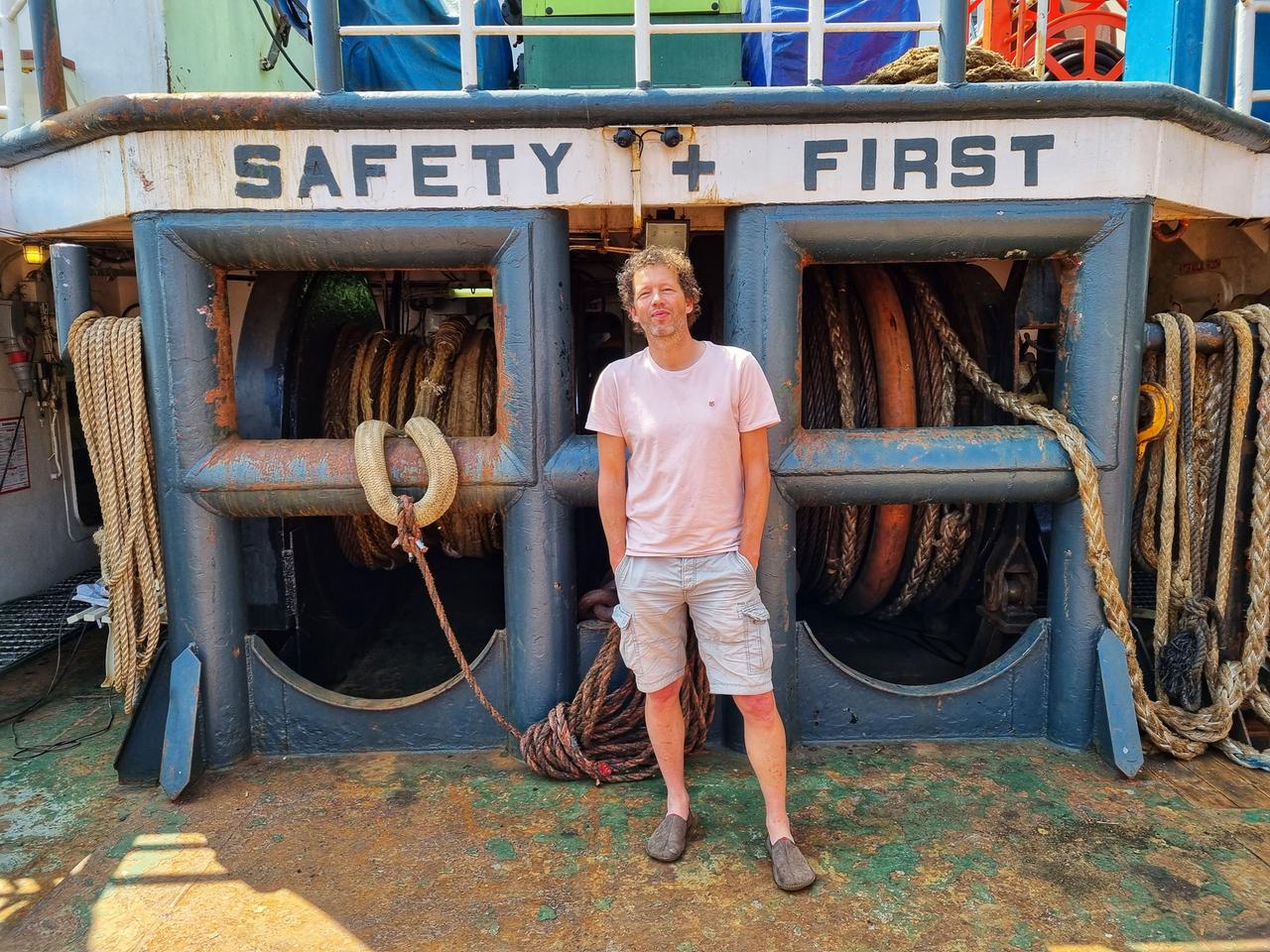 Algenfarmer Joost Wouters aus den Niederlanden steht auf einem Boot an der Küste. Er trägt kurze Hose und T-Shirt. Die Sonne scheint. Algenfarmer Joost Wouters aus den Niederlanden steht auf einem Boot an der Küste. Er trägt kurze Hose und T-Shirt. Die Sonne scheint.