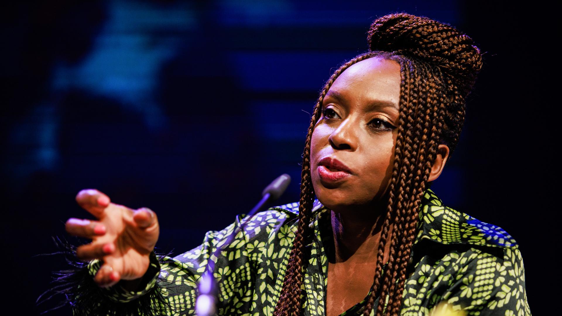 Chimamanda Ngozi Adichie spricht in ein Mikrofon und unterstreicht ihre Worte mit einer zupackenden Geste. Chimamanda Ngozi Adichie spricht in ein Mikrofon und unterstreicht ihre Worte mit einer zupackenden Geste.