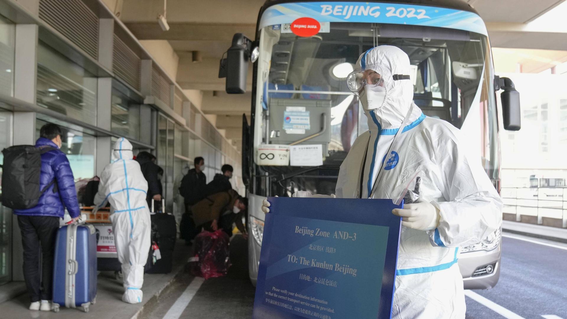 Ein Offizieller trägt Schutzkleidung, während der Journalisten empfängt, die vor den Olympischen Spielen in Peking ankommen. Ein Offizieller trägt Schutzkleidung, während der Journalisten empfängt, die vor den Olympischen Spielen in Peking ankommen.
