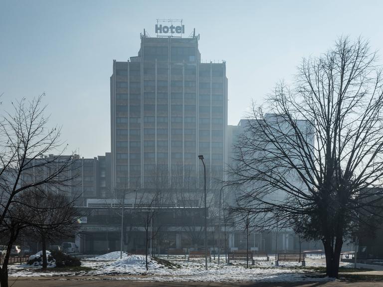 Ein tristes Hochhaus mit der Aufschrift "Hotel" auf dem Dach steht in einer verschneiten Stadt.