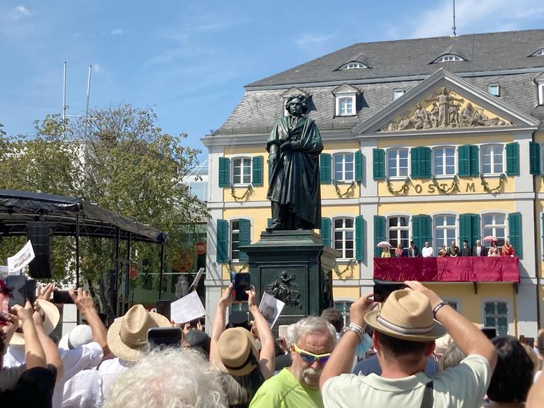 Menschen fotografieren ein Denkmal mit der Statue des Komponisten Ludwig van Beethoven.