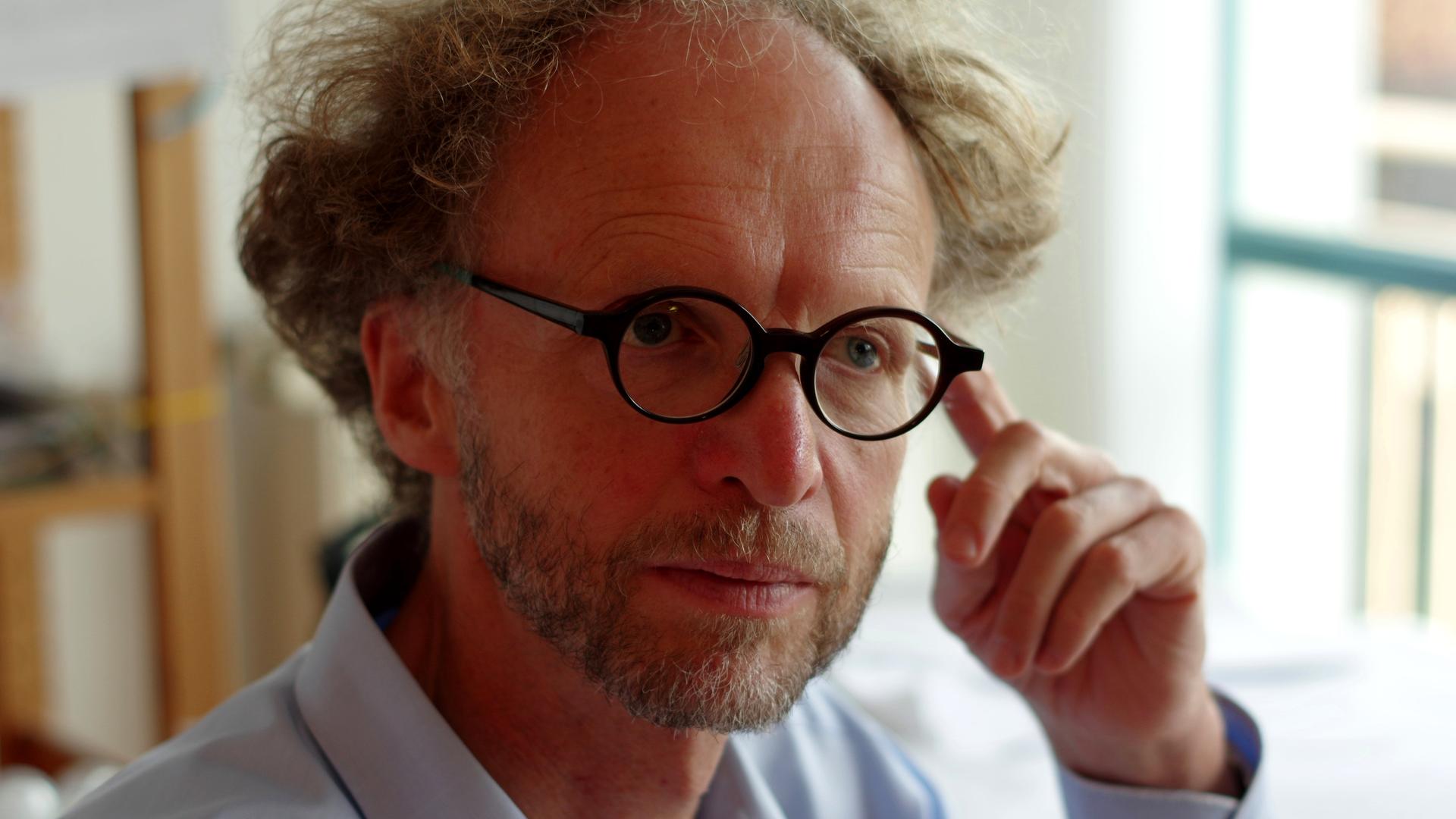 Ein Mann mit Brille legt den Finger an die Schläfe Ein Mann mit Brille legt den Finger an die Schläfe
