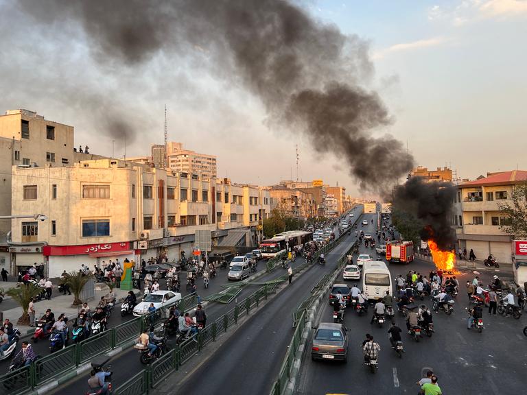 Protest im Iran: Ein Motorrad brennt in Teheran auf der Strasse, Strassenchaos drumherum. Iran, 8. Oktober 2022. 