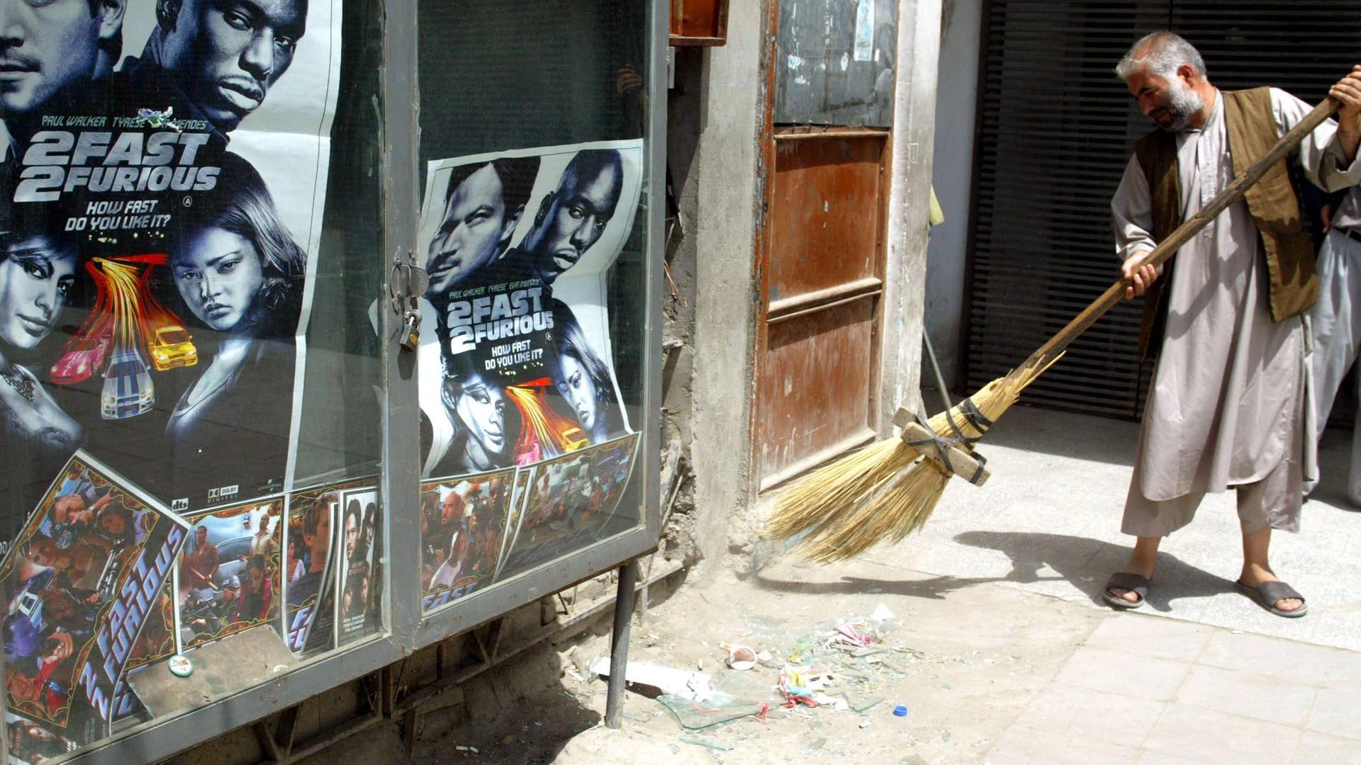 Ein Mann fegt nach einem Bombenanschlag in Kabul Glasscherben von einem zersprungener Fenster zusammen, 2006.
