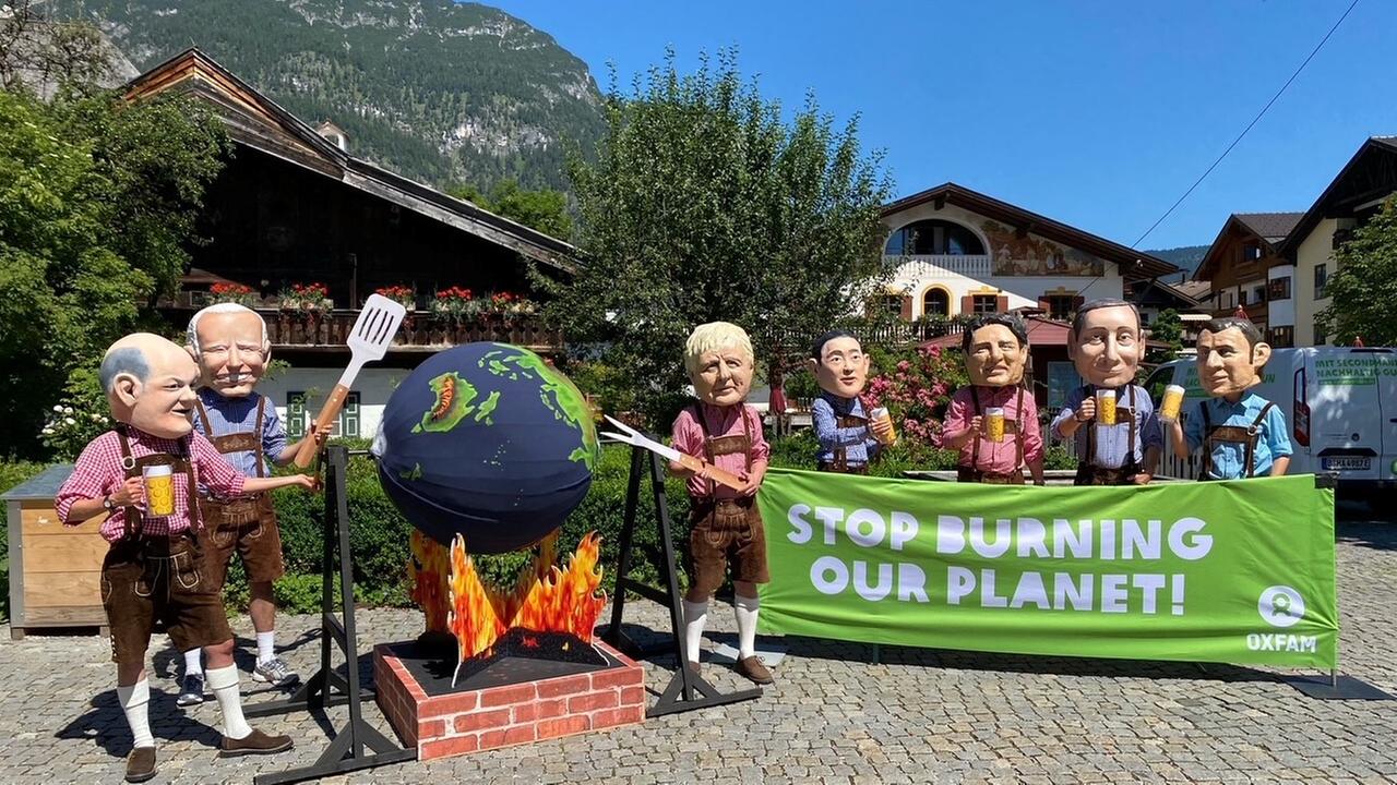 Aktivisten von Oxfam protestieren mit Politiker-Köpfen am Rande des G7-Gipfels auf Schloss Elmau gegen die Klimapolitik der Industrienationen. Die Figuren Scholz. Biden und Johnson drehen dabei eine Weltkugel aus Pappmaché über einer Feuerstelle aus Pappe. Aktivisten von Oxfam protestieren mit Politiker-Köpfen am Rande des G7-Gipfels auf Schloss Elmau gegen die Klimapolitik der Industrienationen. Die Figuren Scholz. Biden und Johnson drehen dabei eine Weltkugel aus Pappmaché über einer Feuerstelle aus Pappe.