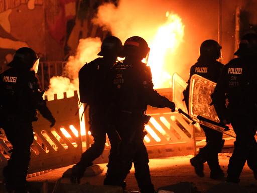 Polizisten gehen an einer brennenden Barrikade im Leipziger Stadtteil Connewitz vorbei, wo es zu Ausschreitungen gekommen ist. 