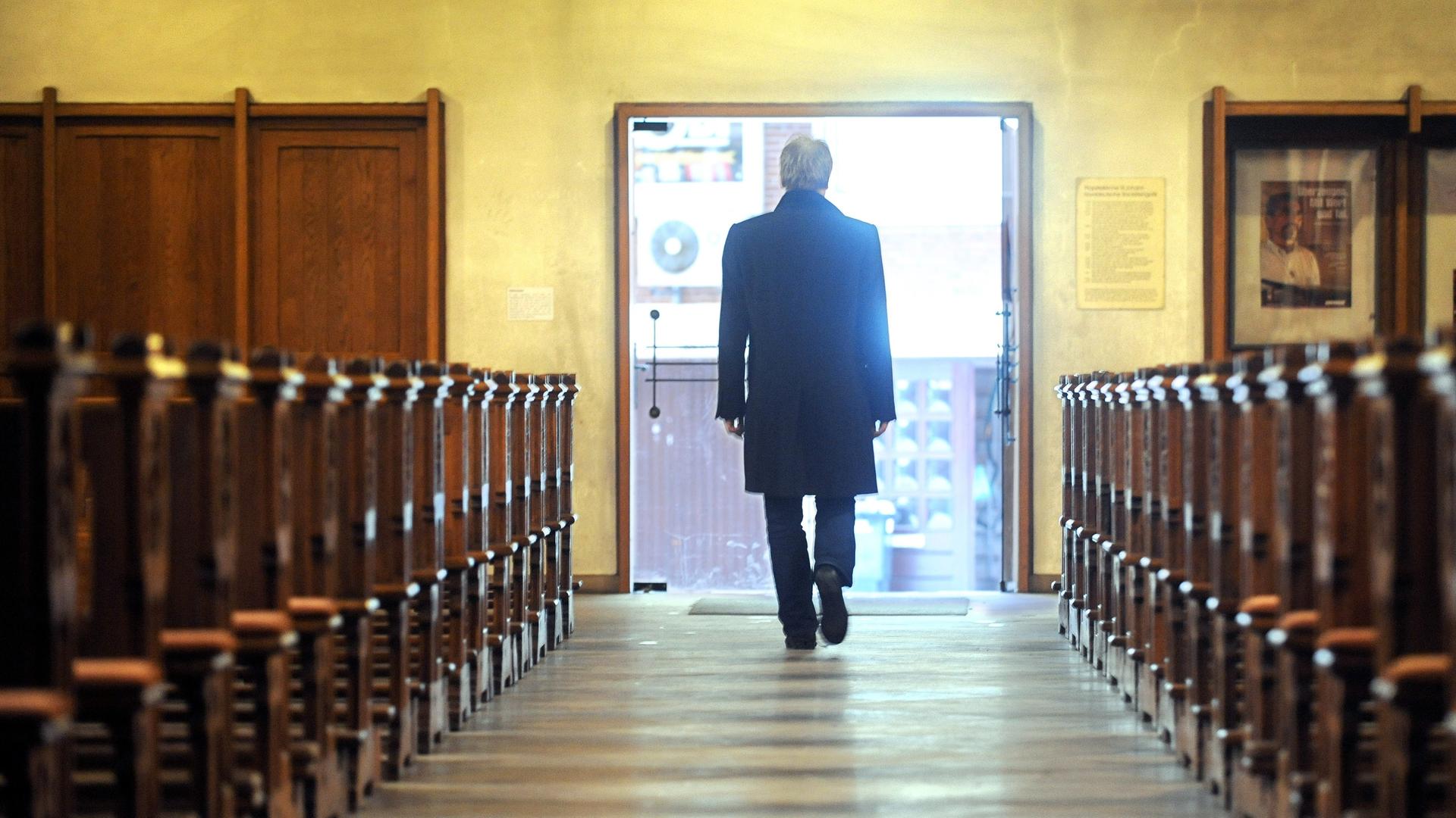 Symbolbild: Ein Mann verlässt eine Kirche - dem Betrachter wendet er den Rücken zu Symbolbild: Ein Mann verlässt eine Kirche - dem Betrachter wendet er den Rücken zu