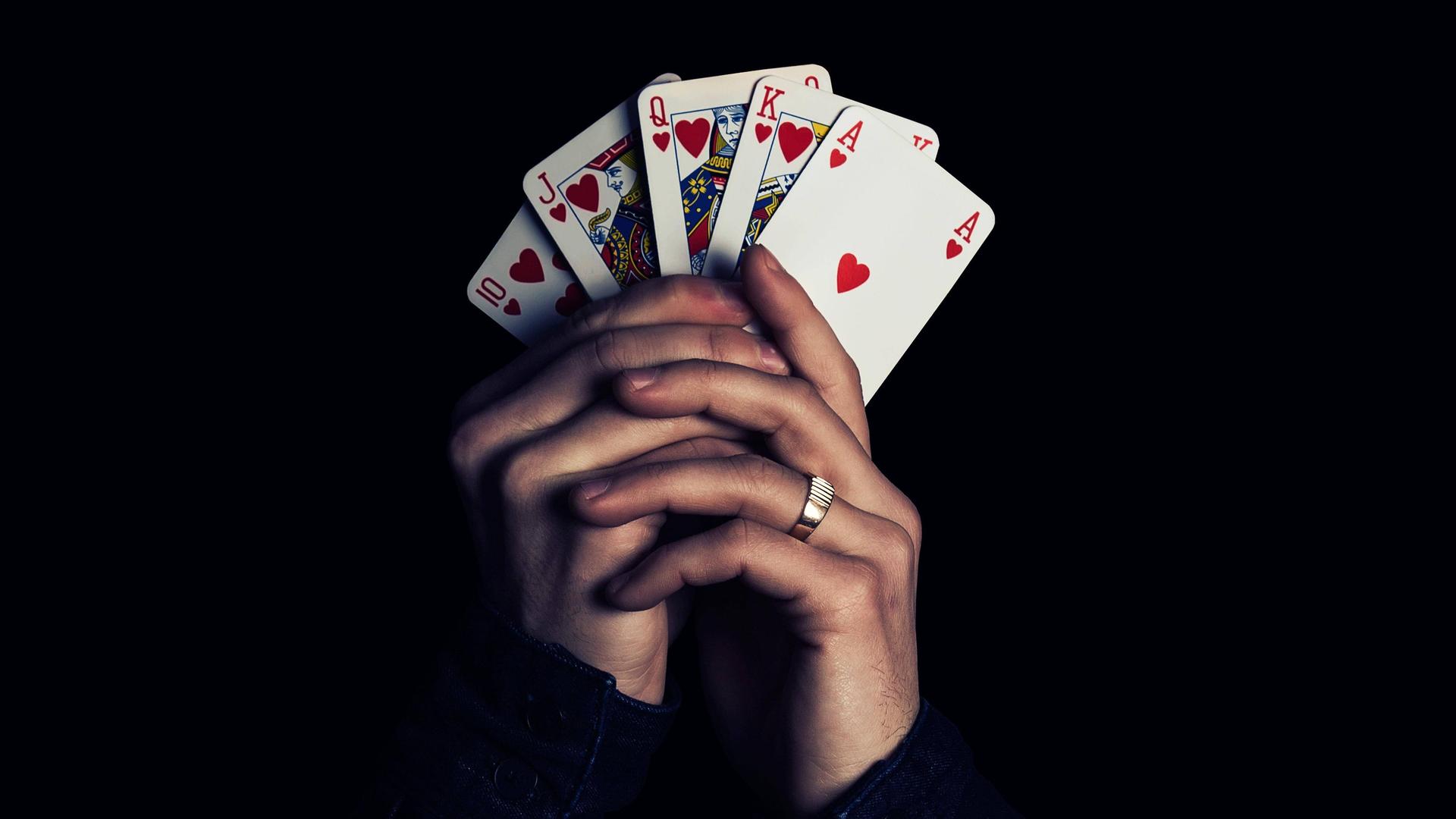 Zwei Hände fächern fünf Spielkarten auf und halten sie in die Kamera, Herz Zehn, Bube, Dame, König, Ass. Zwei Hände fächern fünf Spielkarten auf und halten sie in die Kamera, Herz Zehn, Bube, Dame, König, Ass.