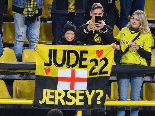 Ein junger Dortmund-Fan bittet Jude Bellinghammit einem Plakat um sein Trikot das ihm Bellinghorm (vorne) gibt. 