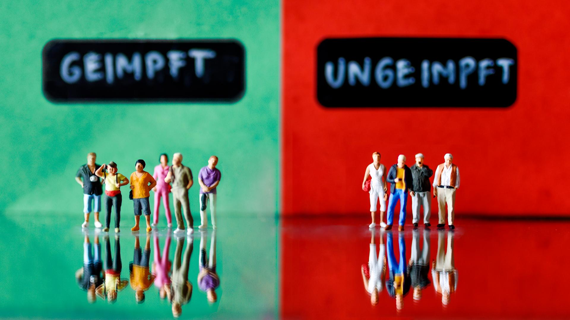 Figurengruppen stehen sich gegenüber, auf der einen Seite die Geimpften und auf der anderen Seite die Ungeimpften. Figurengruppen stehen sich gegenüber, auf der einen Seite die Geimpften und auf der anderen Seite die Ungeimpften.