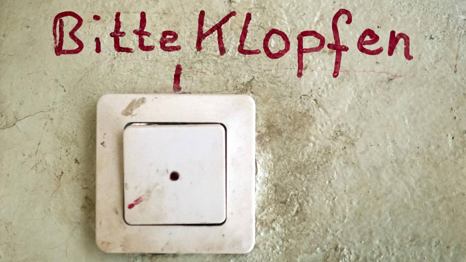 Unfassbare Vorkommnisse während eines Entmietungsprozesses - erzählt von betroffenen Bewohnern. Zu sehen: Eine Haustürklingel an einer Wand mit einem Schriftzug "Bitte klopfen" darüber. Unfassbare Vorkommnisse während eines Entmietungsprozesses - erzählt von betroffenen Bewohnern. Zu sehen: Eine Haustürklingel an einer Wand mit einem Schriftzug "Bitte klopfen" darüber.