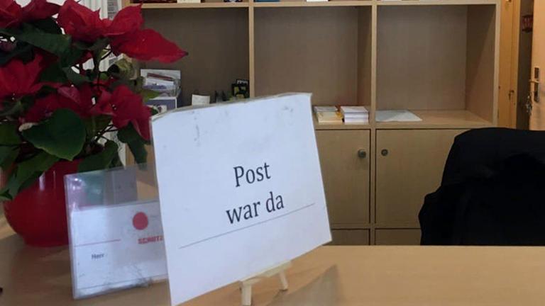 Auf einem Pförtnerschreibtisch steht ein Schild mit der Aufschrift "Post war da". Auf einem Pförtnerschreibtisch steht ein Schild mit der Aufschrift "Post war da".