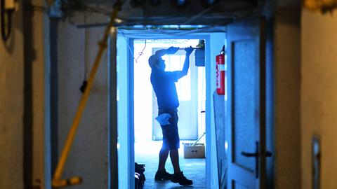 Ein Handwerker arbeitet in einem noch nicht fertig gebauten Haus an einer Tür.
