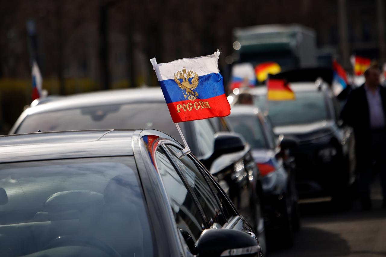 Flaggen mit den russischen Nationalfarben und dem russischen Staatswappen wehen an einem Auto auf dem Olympiaplatz vor dem Olympiastadion. Etwa 900 Menschen haben am Sonntag in Berlin an einem Autokorso mit russischen Fahnen teilgenommen. Flaggen mit den russischen Nationalfarben und dem russischen Staatswappen wehen an einem Auto auf dem Olympiaplatz vor dem Olympiastadion. Etwa 900 Menschen haben am Sonntag in Berlin an einem Autokorso mit russischen Fahnen teilgenommen.