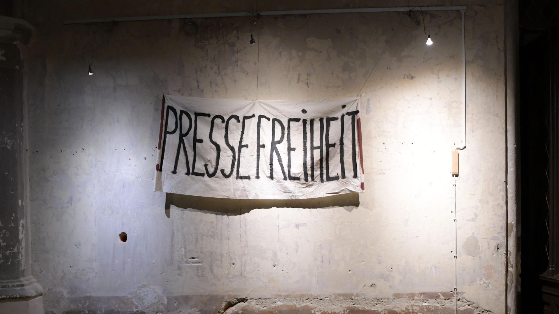 Auf einer Wand ist ein Banner aufgehängt mit der Aufschrift "PRESSEFREIHEIT".