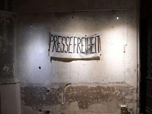 Auf einer Wand ist ein Banner aufgehängt mit der Aufschrift "PRESSEFREIHEIT".