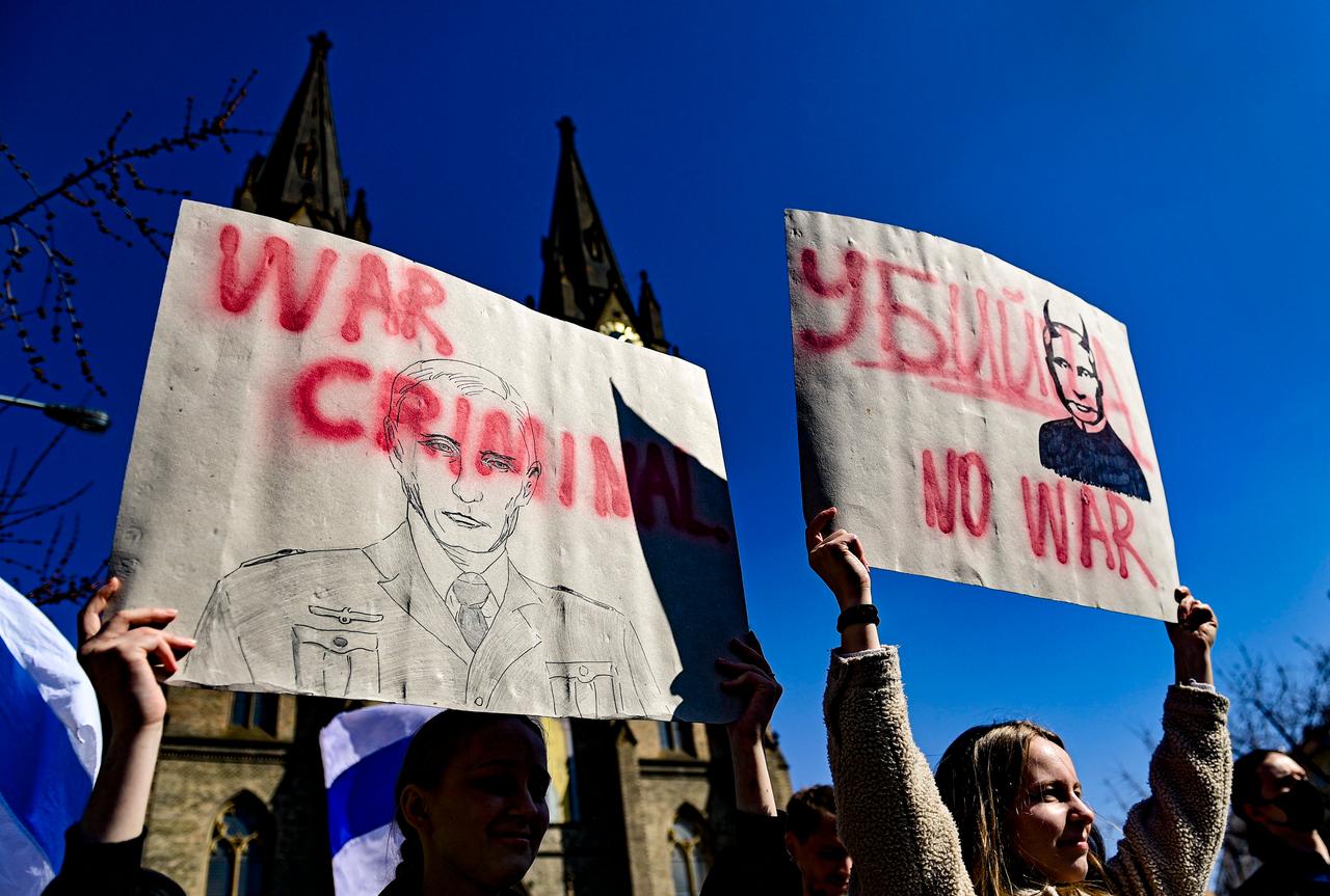 Zwei junge Frauen halten vor der Ludmila Kirche in Prag Plakate hoch, in denen Outin als Kriegsverbrecher bezeichnet wird. Zwei junge Frauen halten vor der Ludmila Kirche in Prag Plakate hoch, in denen Outin als Kriegsverbrecher bezeichnet wird.