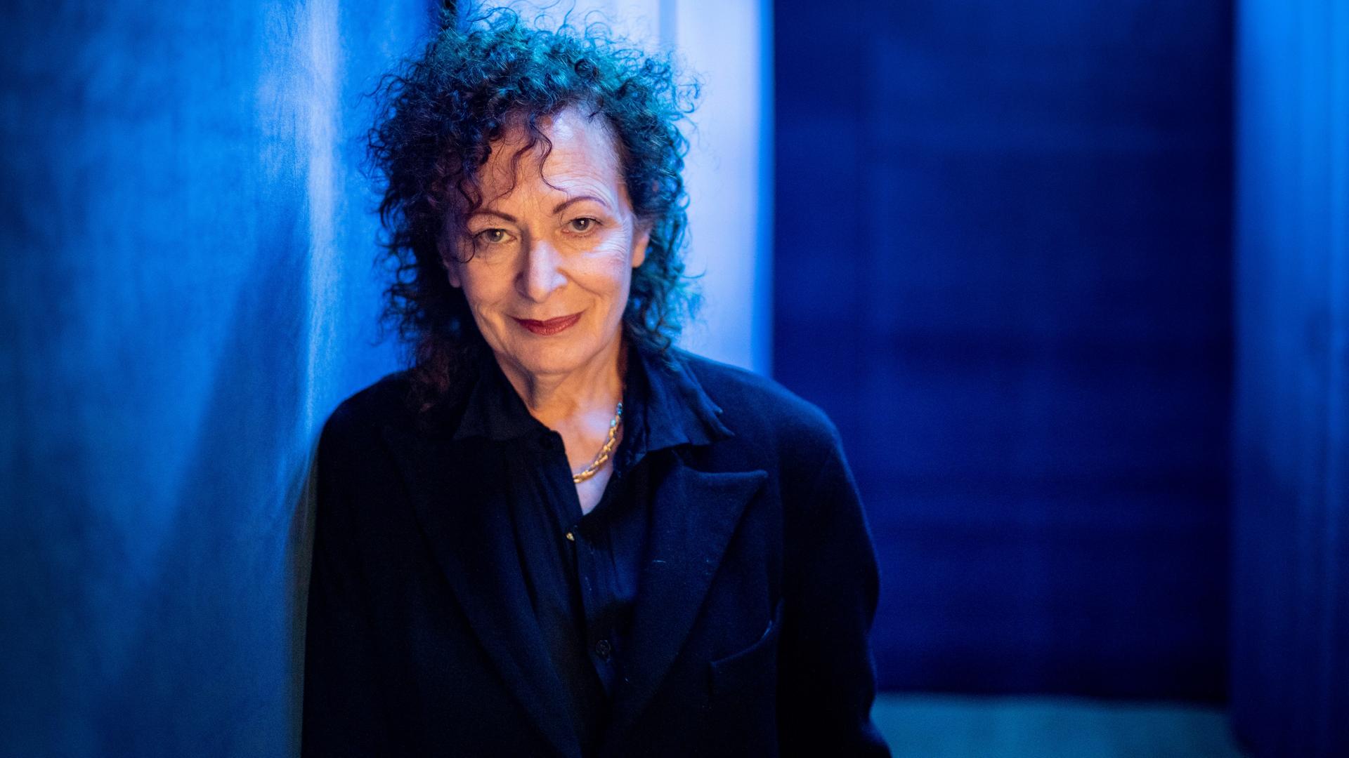 Porträt der Fotografin Nan Goldin vor einem blauen Hintergrund Porträt der Fotografin Nan Goldin vor einem blauen Hintergrund