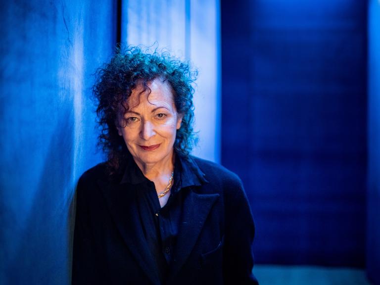 Porträt der Fotografin Nan Goldin vor einem blauen Hintergrund