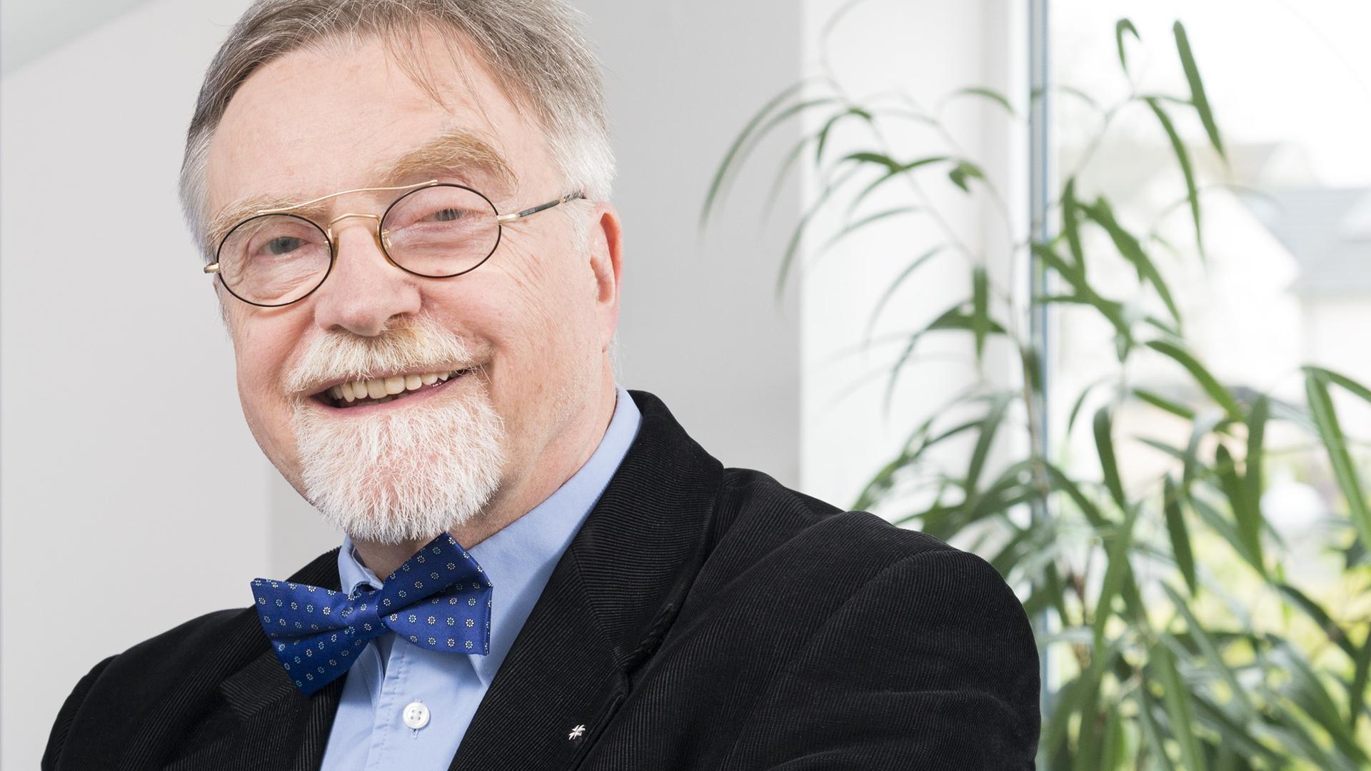 Der Sicherheitsberater Rainer von zur Mühlen lächelt in die Kamera. Er trägt eine große runde Brille und hat einen grauen Bart. Der Sicherheitsberater Rainer von zur Mühlen lächelt in die Kamera. Er trägt eine große runde Brille und hat einen grauen Bart.