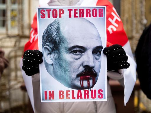 Ein Teilnehmer einer Demonstration gegen den belarussischen Machthaber Alexander Lukaschenko in Polen hält ein Plakat in der Hand auf dem steht "Stop Terror in Belarus"