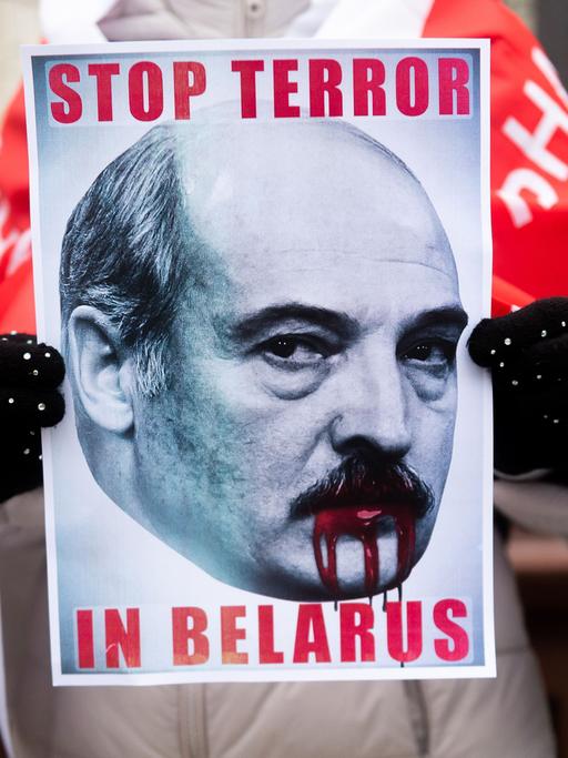 Ein Teilnehmer einer Demonstration gegen den belarussischen Machthaber Alexander Lukaschenko in Polen hält ein Plakat in der Hand auf dem steht "Stop Terror in Belarus"