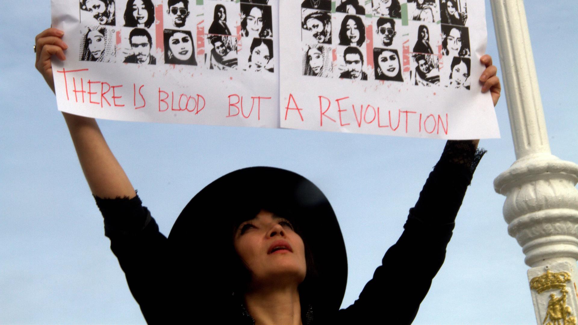 Die Schauspielerin Mitra Farahani protestiert beim Gijón International Film Festival. Sie saß selbst einige Wochen im Iran im Gefängnis, lebt aber inzwischen in Frankreich. Sie hält ein Schild mit Bildern von Opfern der Repression in die Luft. Die Schauspielerin Mitra Farahani protestiert beim Gijón International Film Festival. Sie saß selbst einige Wochen im Iran im Gefängnis, lebt aber inzwischen in Frankreich. Sie hält ein Schild mit Bildern von Opfern der Repression in die Luft.