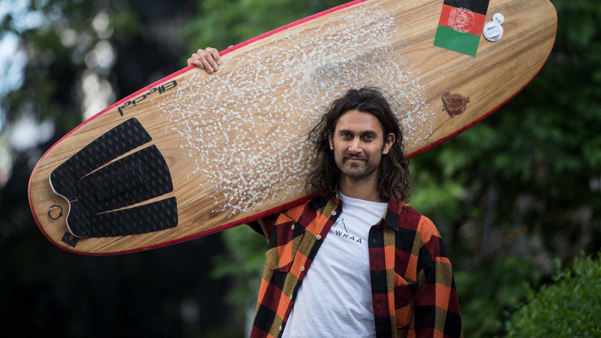 Afridun Amu mit Surfbrett, auf der eine Afghanistan-Flagge klebt. Afridun Amu mit Surfbrett, auf der eine Afghanistan-Flagge klebt.