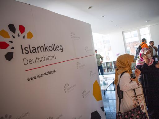 Ein Raum mit einem Flipboard und mehreren Menschen bei der Eröffnung des Islam-Kollegs in Osnabrück