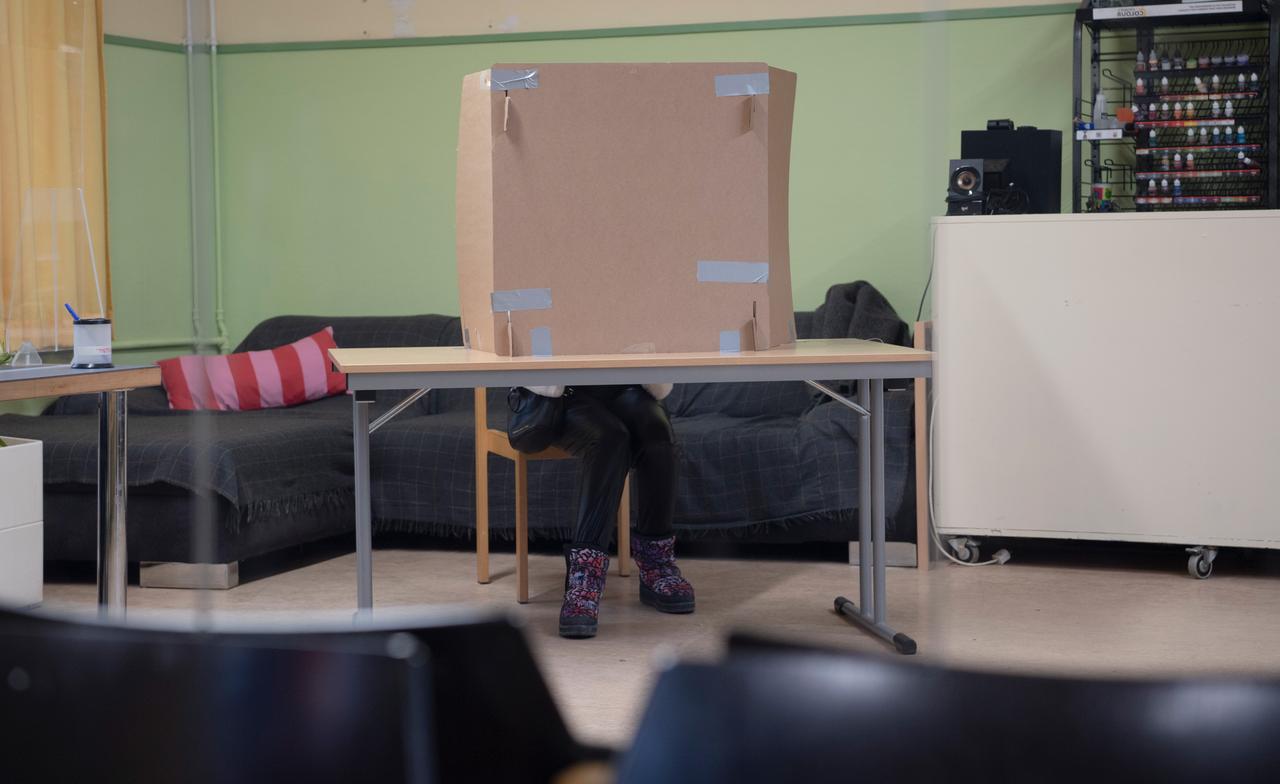 Eine Frau sitzt in einer Wahlkabine eines Wahllokals in Berlin-Schmargendorf.