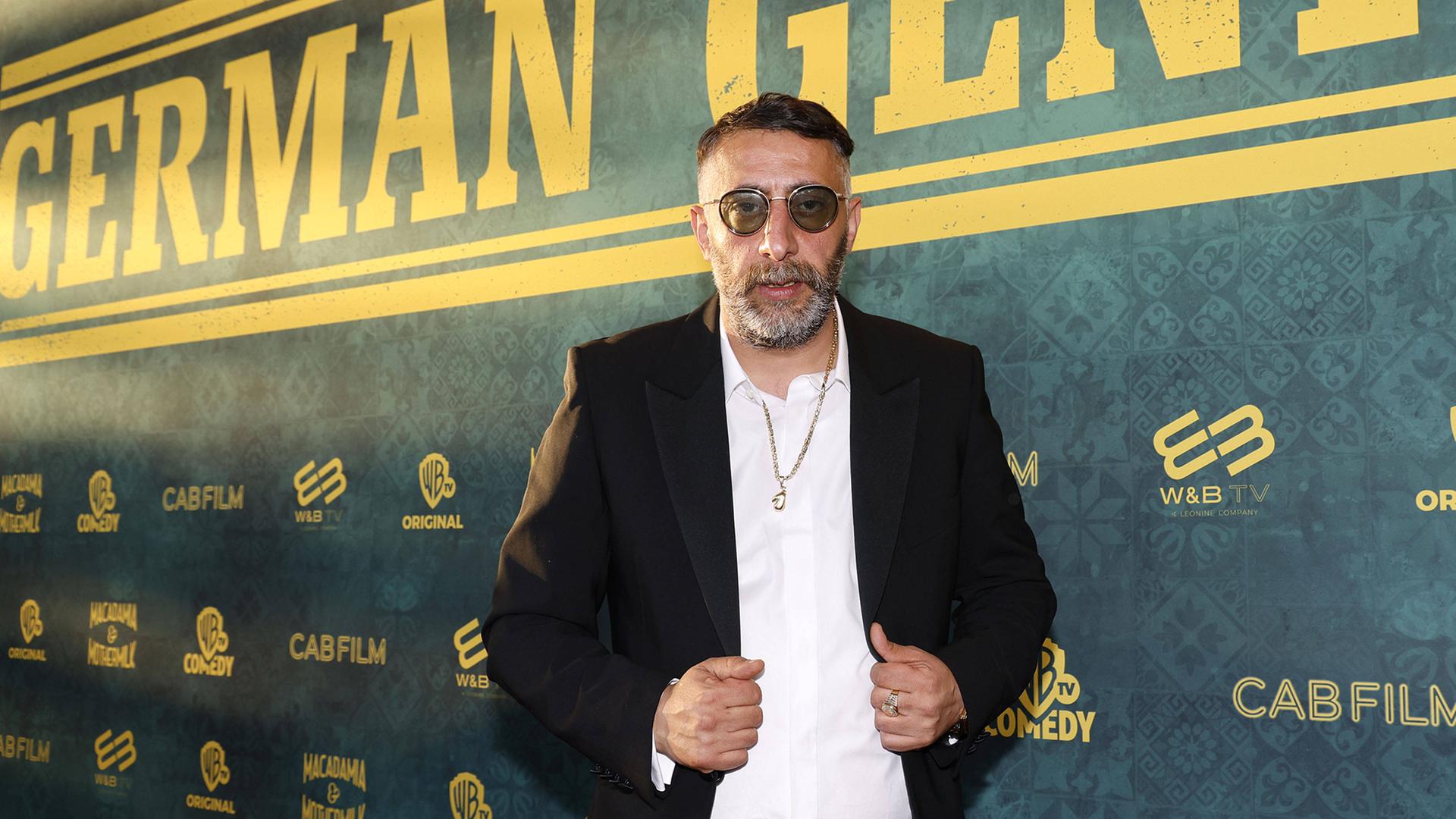 Der Schauspieler Kida Ramadan steht bei der German-Genius-Filmpremiere vor einer Wand mit der Aufschrift "German Genius" Der Schauspieler Kida Ramadan steht bei der German-Genius-Filmpremiere vor einer Wand mit der Aufschrift "German Genius"
