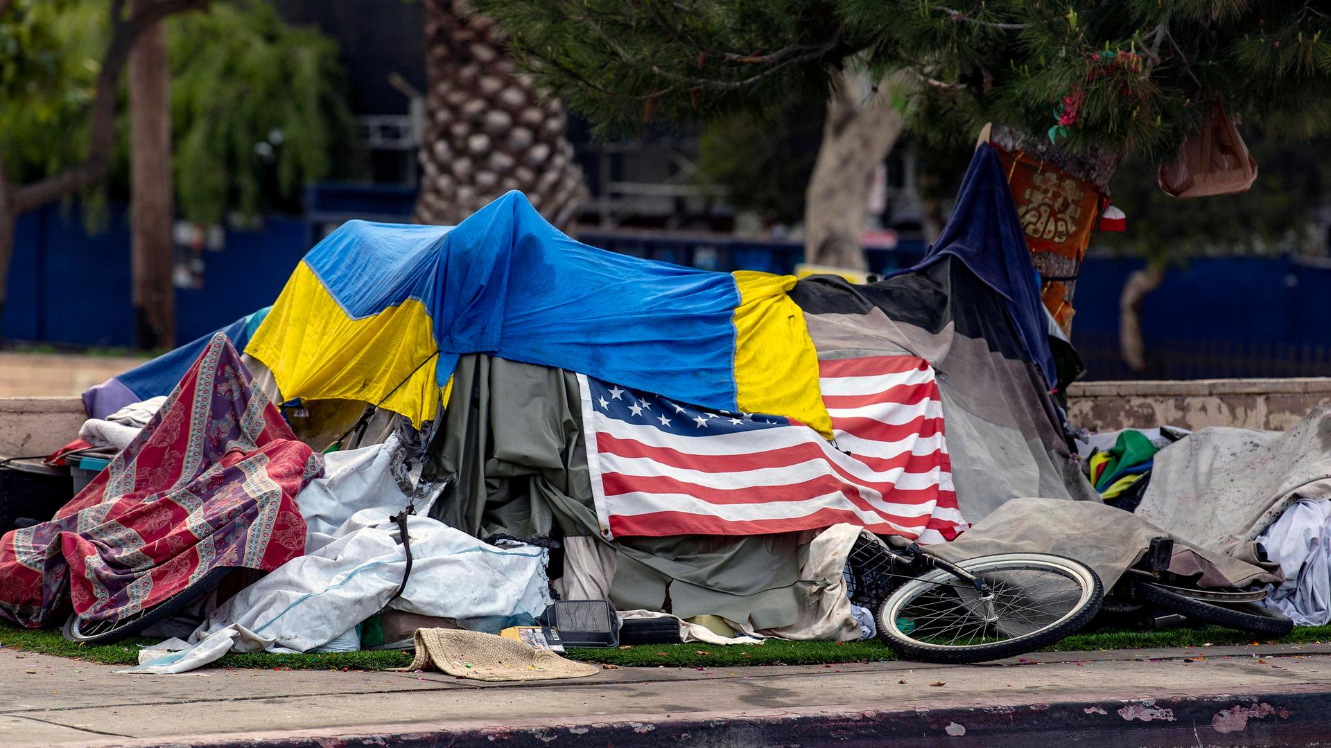 Das Zelt eines Obdachlosen am Straßenrand ist mit der amerikanischen und der ukrainischen Flagge bedeckt. Das Zelt eines Obdachlosen am Straßenrand ist mit der amerikanischen und der ukrainischen Flagge bedeckt.