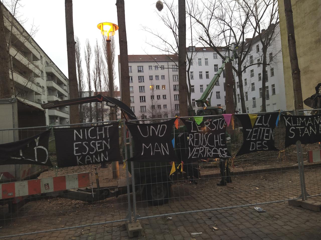 Die Bäume zwischen den Häusern werden gefällt, letzte Protestbanner hängen an einem Zaun. Die Bäume zwischen den Häusern werden gefällt, letzte Protestbanner hängen an einem Zaun.