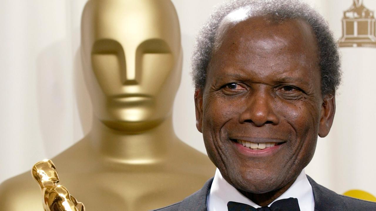 Der schwarze Schauspieler Sidney Poitier steht neben einer großen Oscar-Statue und hält einen Oscar in der Hand Der schwarze Schauspieler Sidney Poitier steht neben einer großen Oscar-Statue und hält einen Oscar in der Hand