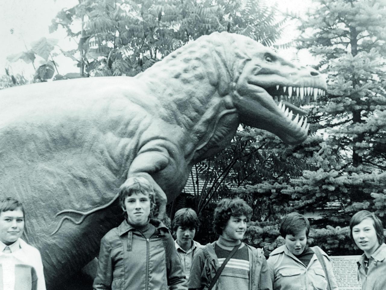 Sechs Jungen haben sich vor dem Modell eines T-Rex aufgestellt.