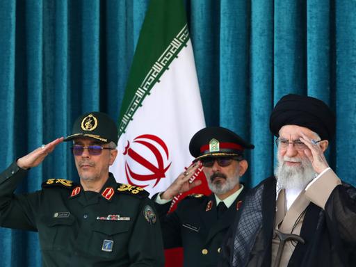 Irans oberster geistlicher Führer Ajatollah Ali Chamenei sitzt neben zwei Militärangehörigen