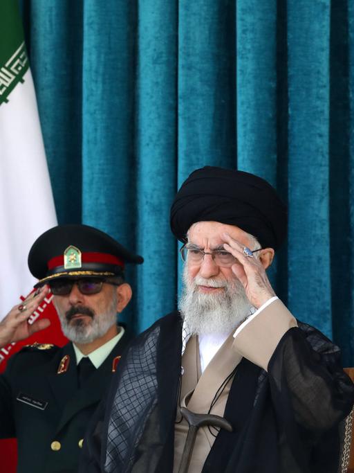 Irans oberster geistlicher Führer Ajatollah Ali Chamenei sitzt neben zwei Militärangehörigen